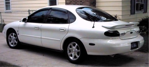 1997 Ford Taurus - White sedan with tinted windows and a rear spoiler is parked in front of a house.