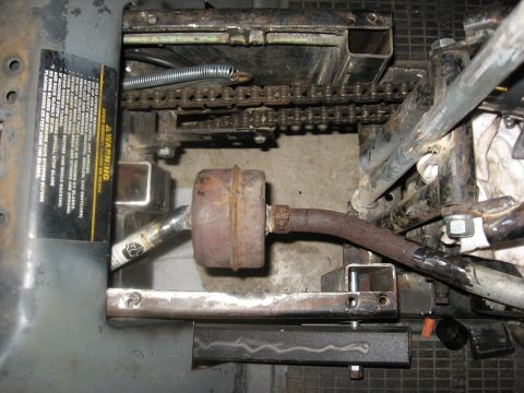 2010 Kawasaki BAYOU 220 - Detail view of the drive chain and exhaust system on a vehicle, showing wear and tear.