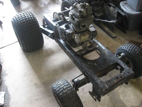 2010 Kawasaki BAYOU 220 - The frame and engine of an ATV are shown in a garage setting.