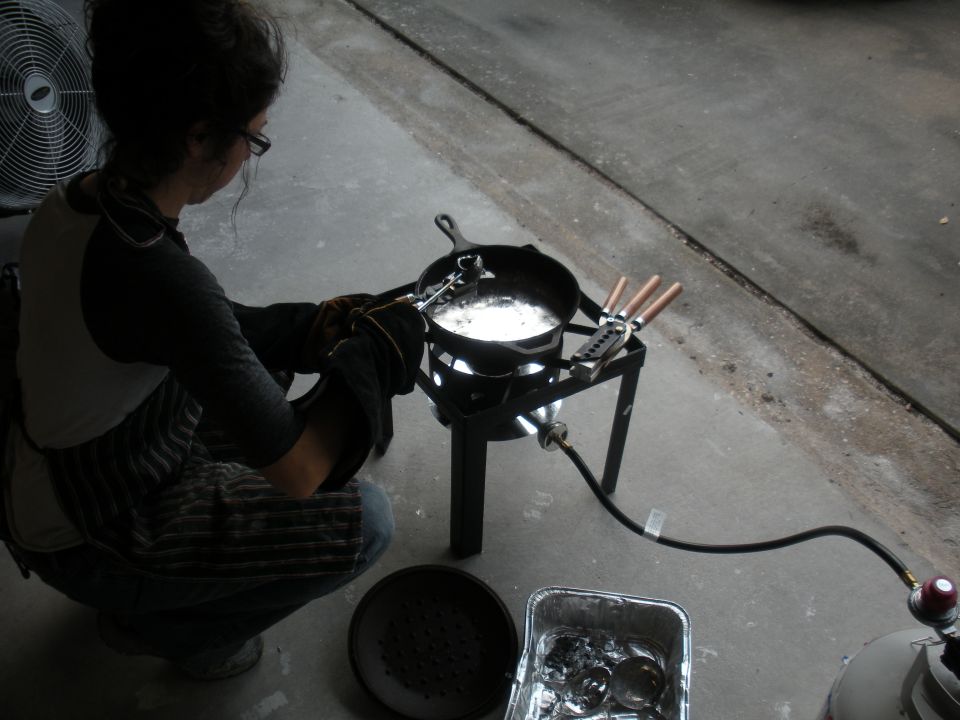Person casting metal over a propane burner