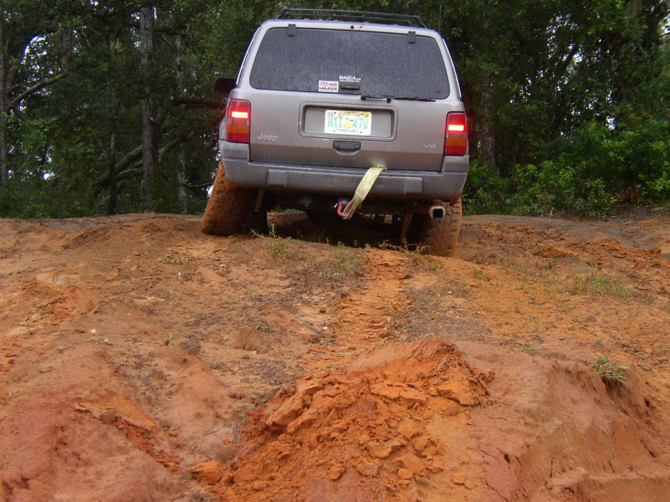Jeep Grand Cherokee on a dirt trail, rear view, with a tow strap attached