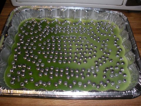 1996 Ford Bronco - Metal balls are submerged in green liquid within a fluted aluminum pan, likely for reloading or casting purposes.
