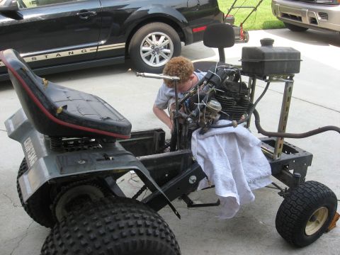 2010 Kawasaki BAYOU 220 - Working on a lawn tractor with a Ford Mustang parked nearby.
