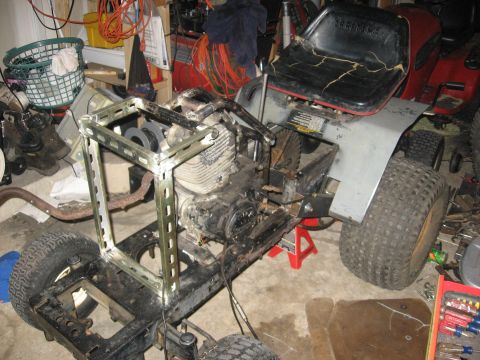 2010 Kawasaki BAYOU 220 - Lawn tractor frame and engine assembly in a garage, with another tractor partially visible.