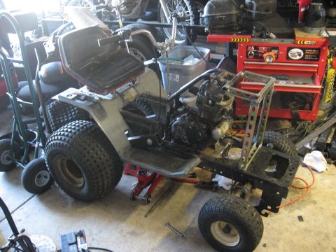 2010 Kawasaki BAYOU 220 - An all-terrain vehicle is disassembled and supported by jack stands in a workshop environment.