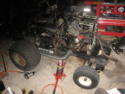 2010 Kawasaki BAYOU 220 - An all-terrain vehicle chassis is shown with its engine exposed and supported by a red jack.