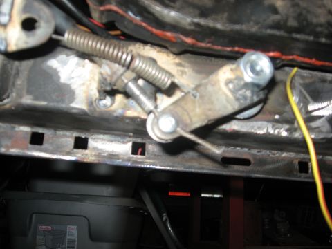 2010 Kawasaki BAYOU 220 - Close-up of a throttle cable mechanism, showing its components and attachment points.