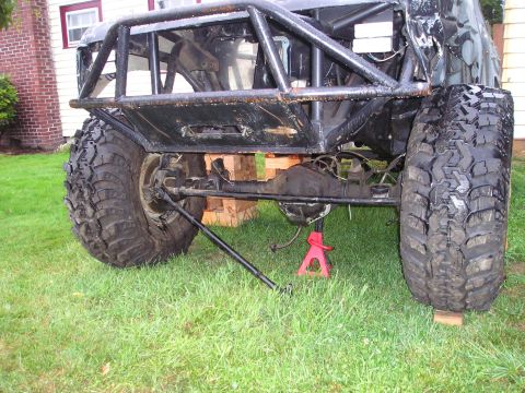1986 Ford Bronco II - Modified off-road vehicle's rear axle and suspension assembly, showing large tires and roll cage structure.