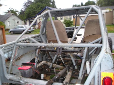 1986 Ford Bronco II - The interior of a custom-built off-road vehicle is visible, a prominent roll cage and exposed mechanical components.