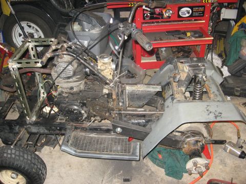 2010 Kawasaki BAYOU 220 - ATV chassis with engine and handlebars, partially disassembled in a garage setting.