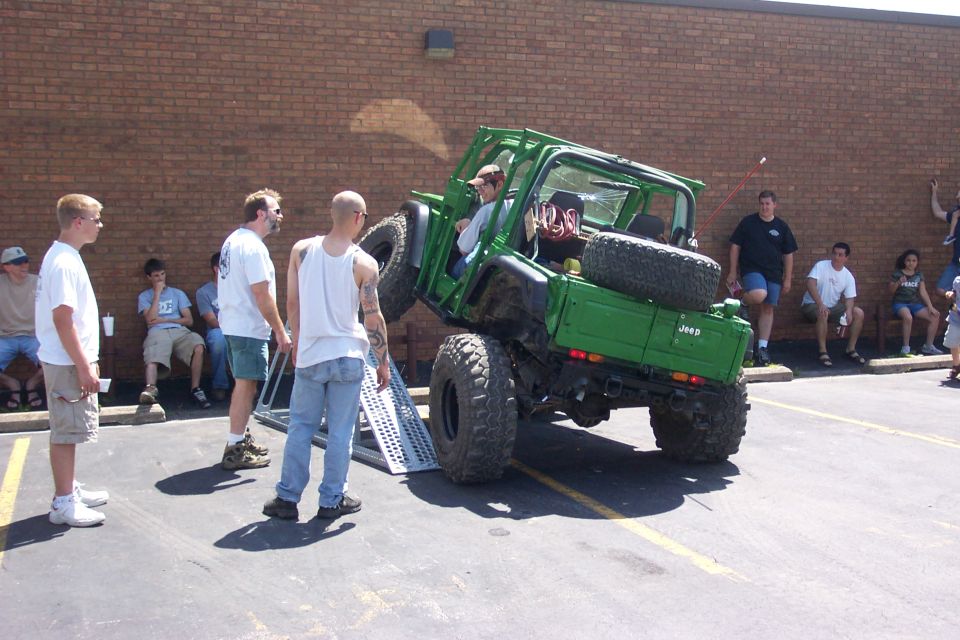 Green Jeep Wrangler on a ramp with people watching