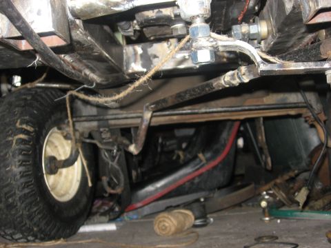 2010 Kawasaki BAYOU 220 - Close-up view of the undercarriage of a vehicle, showing mechanical components and a tire.