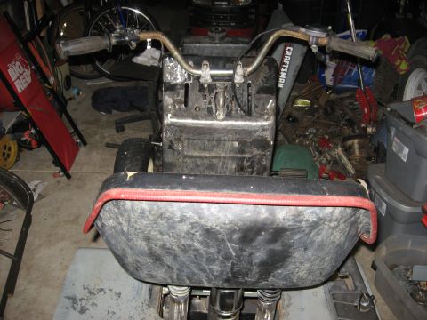 2010 Kawasaki BAYOU 220 - A Craftsman lawn tractor sits in a garage with various items stored around it.