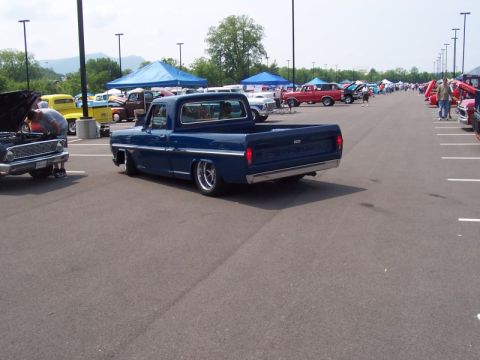 2007 Ford Mustang - Blue pickup truck with custom wheels and lowered suspension at an outdoor car show.