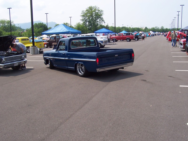 Blue pickup truck with lowered suspension parked in a lot with other vehicles