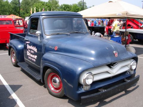 2007 Ford Mustang - A blue 1956 Ford F-series pickup truck with custom paint and lettering is parked at an outdoor event.