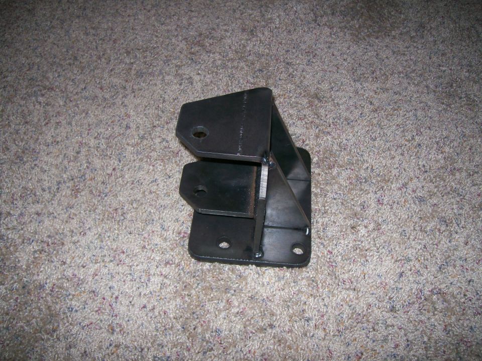 Black metal bracket with multiple mounting holes, sitting on carpet