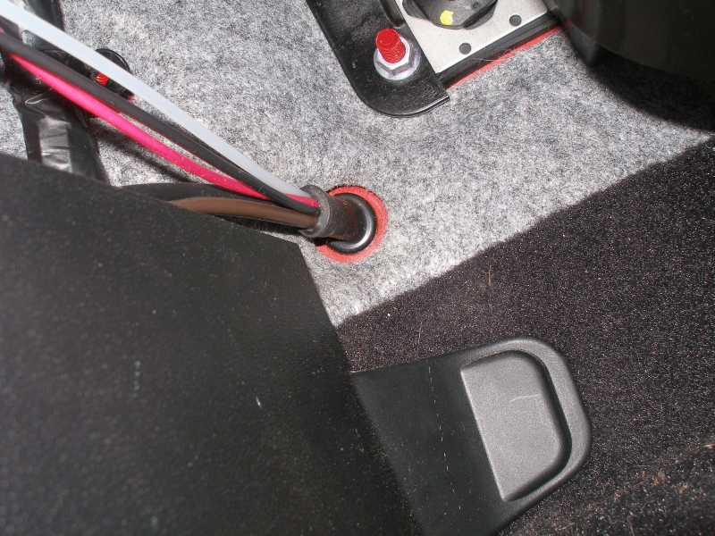 Close-up of wires going through a grommet in a car's carpeted interior