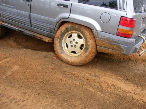 1991 Ford Bronco - Jeep Grand Cherokee's rear wheel stuck deep in mud.