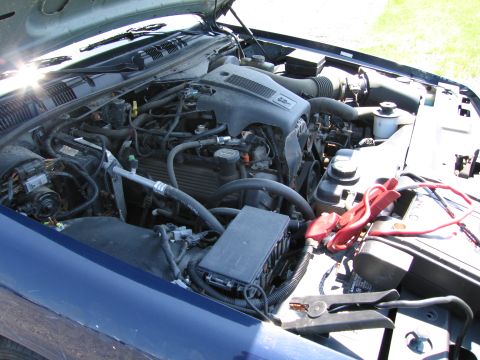 1991 Ford LTD Crown Victoria - Engine bay of a 1991 Ford Crown Victoria LTD, showing the engine and battery with jumper cables connected.