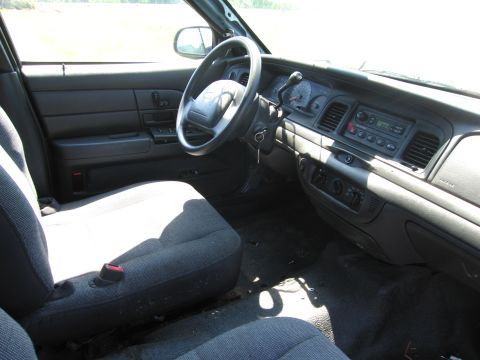 1991 Ford LTD Crown Victoria - The interior of a Ford Crown Victoria shows the driver's side dashboard, steering wheel, and seats in daylight.