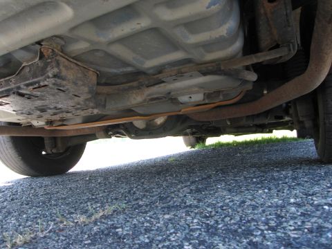 1991 Ford LTD Crown Victoria - The undercarriage of a vehicle, revealing its exhaust pipes and fuel tank components.