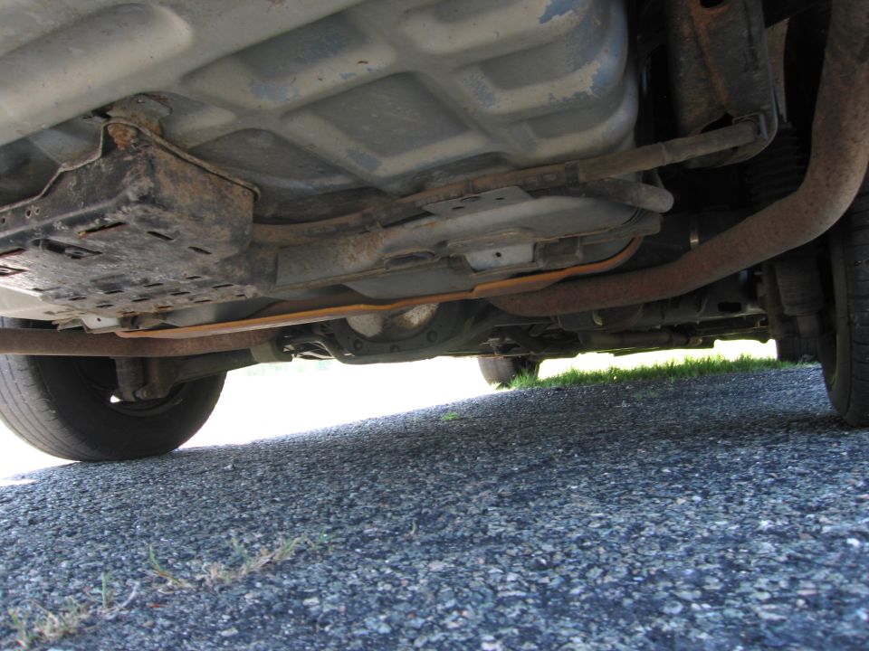 Underside view of a car showing the exhaust system and fuel tank