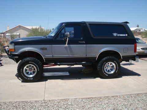 1994 Ford Bronco - This lifted 1994 Ford Bronco is parked on a concrete driveway under a clear blue sky.