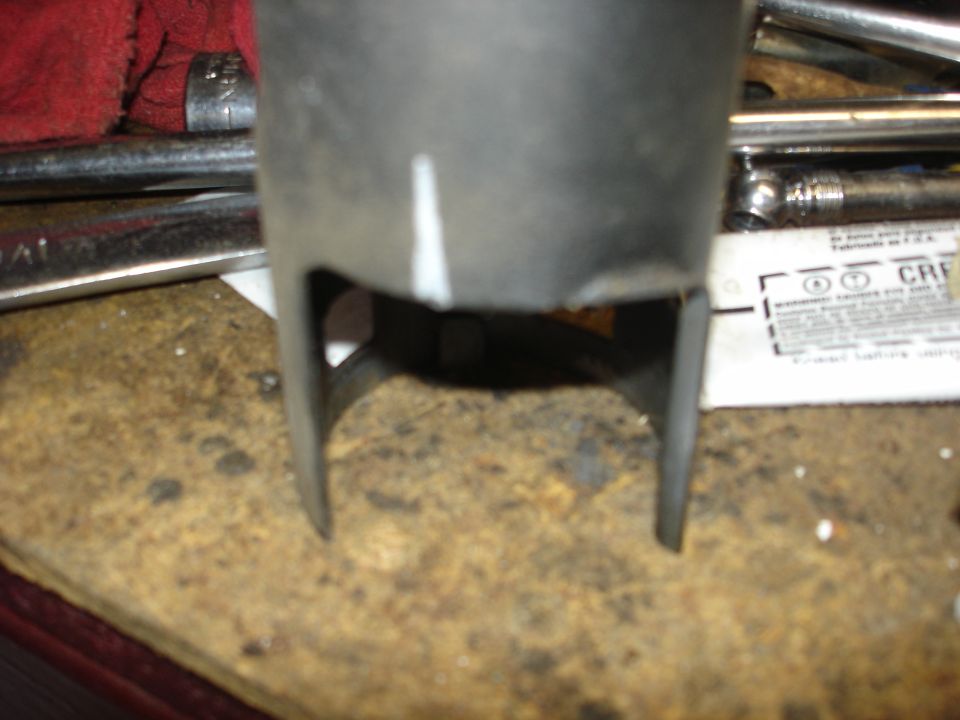 Close-up of a metal exhaust pipe over a pile of wood chips