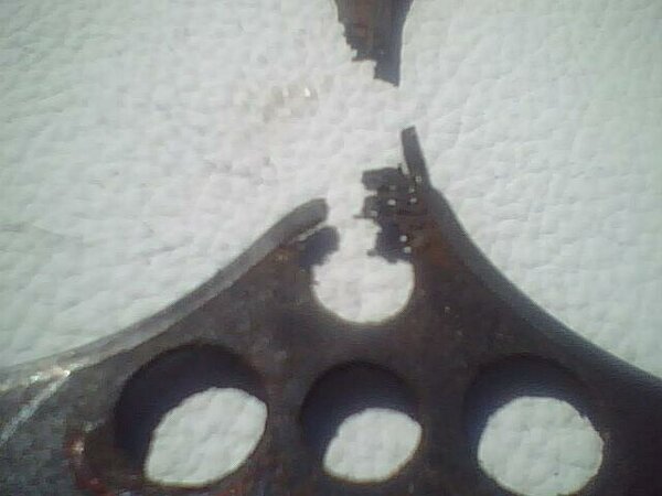 close-up of a broken, rusty metal piece with several circular cutouts