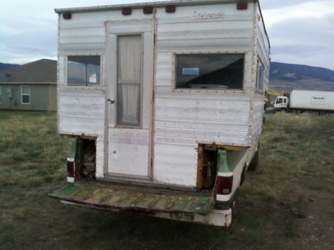 2006 Ford E350 - A camper is mounted on the bed of a pickup truck, viewed from the rear.