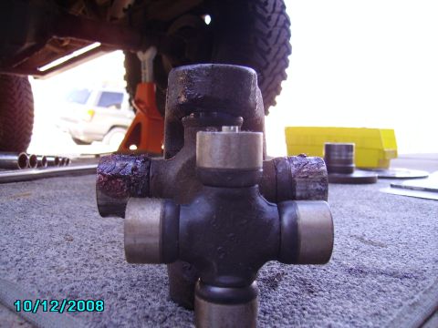 1978 Ford Bronco - Close-up of a universal joint, with a vehicle on a jack visible in the background.