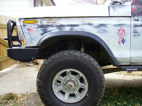 1978 Ford Bronco - Close-up of a 1978 Ford Bronco's front fender, showing the wheel, bumper, and some decals.