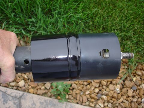 1979 Ford F-250 - A black painted steering column part is held by a hand outdoors, with grass and rocks in the background.