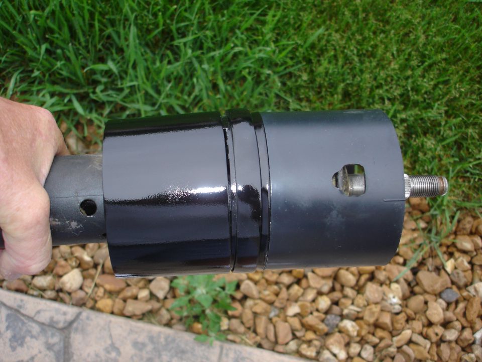 Black painted steering column part held by a hand, with a threaded shaft visible