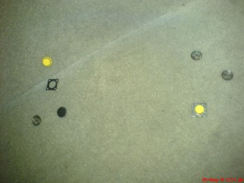 1998 Ford Crown Victoria - Various small automotive parts and coins are laid out on a carpeted surface, with a watermark indicating 'Supermotors.net'.
