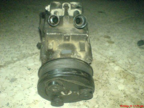 1998 Ford Crown Victoria - A dirty A/C compressor with a pulley and two hose fittings is shown.