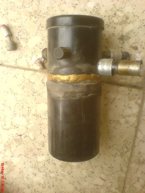 1998 Ford Crown Victoria - A black car air conditioning receiver drier with brass fittings is shown, possibly for a 1998 Ford Crown Victoria.