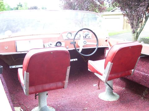 1979 Ford Bronco - The interior of a boat features red vinyl seats and carpeting, with a steering wheel and dashboard visible.