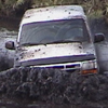 1993 Ford Bronco - A white van is submerged in thick mud, with only the top half visible.