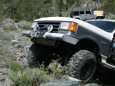 1982 Ford Bronco - This lifted 1982 Ford Bronco navigates a rocky trail, equipped with a winch and auxiliary lights.