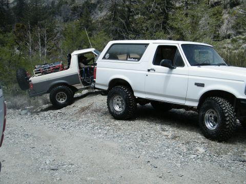 1982 Ford Bronco - A white 1992 Ford Bronco tows a second-generation Bronco off-road.