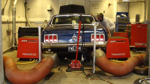 1970 Ford Mustang - A blue 1969 Ford Mustang is positioned on a dynamometer in a workshop setting.
