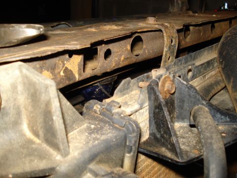 1985 Ford F-150 - Close-up of a rusty bracket on a vehicle's radiator support structure.