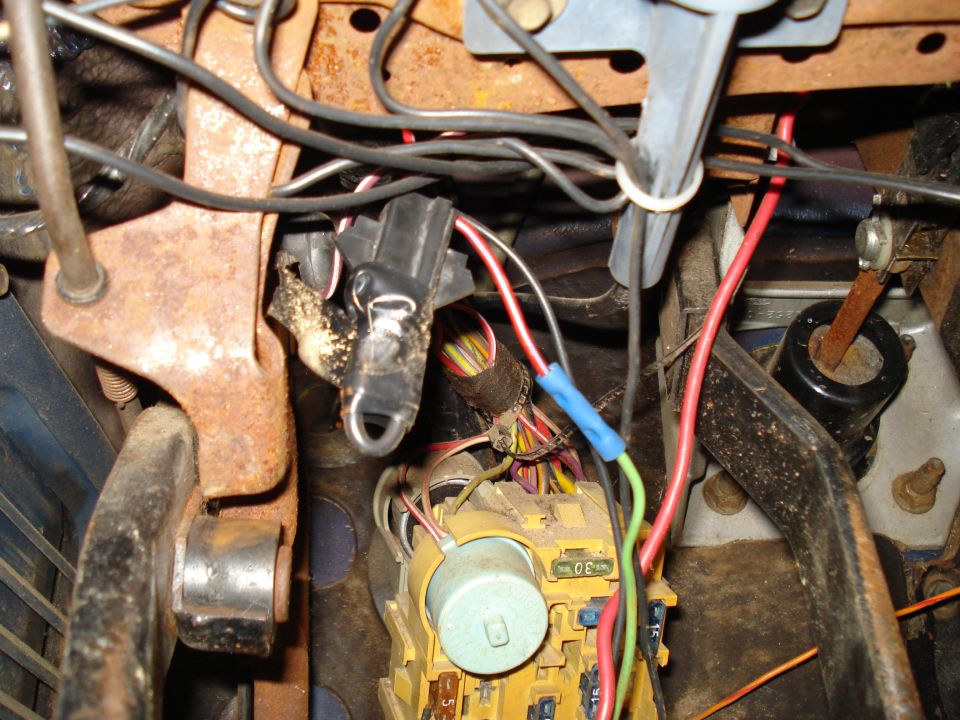 Close-up of a vehicle's wiring harness and fuse box with various colored wires and connectors