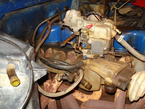 1985 Ford F-150 - Close-up view of engine components, including a carburetor, within a blue engine bay.