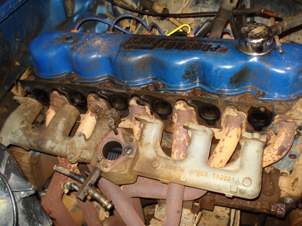 Ford V8 engine with blue valve covers and rusty exhaust manifolds. Part number 133624 visible