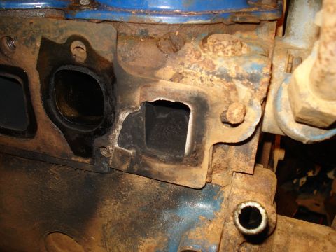 1985 Ford F-150 - Close-up view of a heavily rusted engine exhaust manifold, showing the ports for exhaust gases.