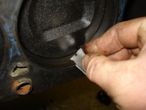 1991 Ford Bronco - A hand uses a metal scraper to clean the inside of an engine cylinder.