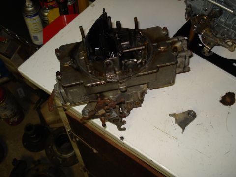 1967 Ford F-250 - A close-up view of a carburetor, likely for an older vehicle, resting on a workbench.